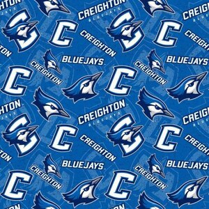 May include: A blue and white fabric with a repeating pattern of the Creighton Bluejays logo. The logo features a blue jay bird with a white 'C' and the words 'Creighton Bluejays'.