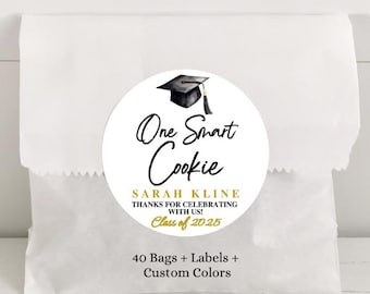 Könnte beinhalten: Runder weißer Aufkleber mit einer schwarzen Graduation Cap und dem Text "One Smart Cookie" in schwarzer Schrift. Unter dem Text steht der Name "SARAH KLINE" in goldener Schrift, gefolgt von "THANKS FOR CELEBRATING WITH US!" in kleinerer goldener Schrift. Der Text "Class of 2025" steht in goldener Schrift darunter. Der Aufkleber befindet sich auf einem weißen Papierbeutel.
