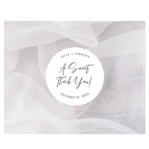 May include: A white circle with black text on a white sheer fabric background. The text reads "Julia & Timothy, A Sweet Thank You! October 19, 2024".