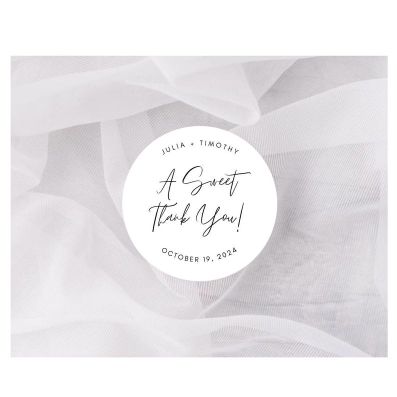 May include: A white circle with black text on a white sheer fabric background. The text reads "Julia & Timothy, A Sweet Thank You! October 19, 2024".