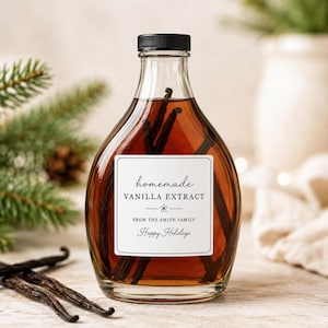 May include: A clear glass bottle filled with amber-colored liquid and dark vanilla beans. The white label reads: homemade VANILLA EXTRACT, FROM THE SMITH FAMILY, Happy Holidays. The bottle has a black screw cap and a rounded, tapered shape.