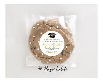 May include: A white round sticker with black and gold text. The sticker says "A sweet ending to a new beginning! Keylani's Graduation Thanks for celebrating with us! Class of 2025". A black graduation cap with a gold tassel is on top of the text. The sticker is on a brown cookie with white polka dots.