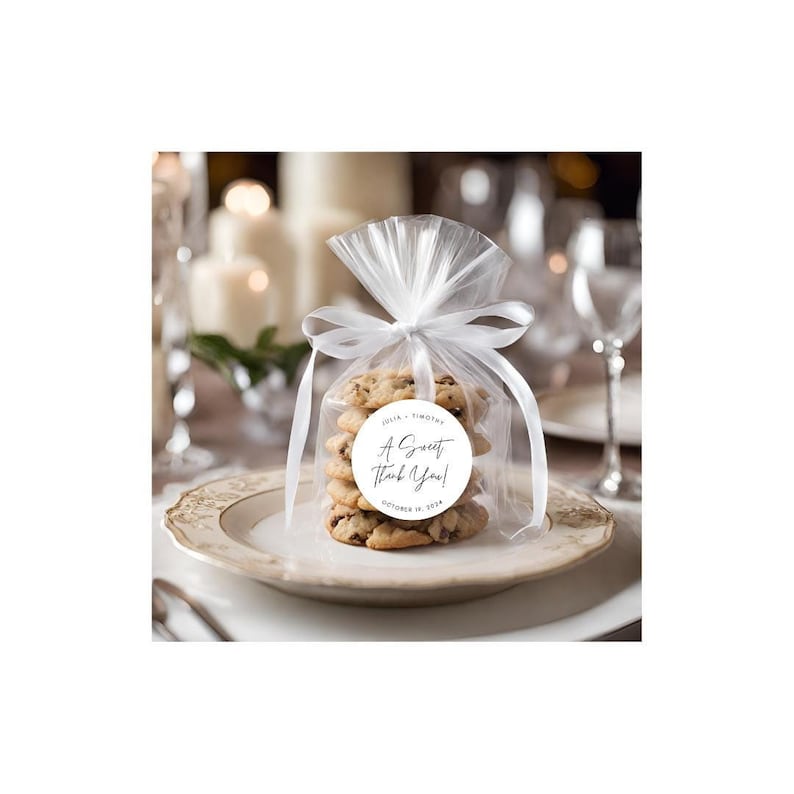 May include: A white round sticker with the text "A Sweet Thank You!" and the names "Julia & Timothy" and the date "October 18, 2018". The sticker is on a clear cellophane bag filled with chocolate chip cookies.