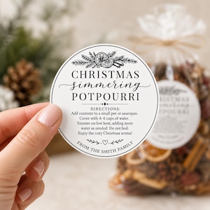 May include: A circular white label with black text reading CHRISTMAS simmering POTPOURRI, directions for use, and FROM THE SMITH FAMILY. The design features black line art of pine branches, orange slices, and cinnamon sticks at the top and bottom.