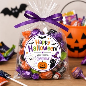 May include: A clear plastic treat bag filled with assorted candies in orange, purple, and black wrappers, tied with a purple ribbon. A circular sticker on the front reads Happy Halloween! your friend, Gemma, with icons of a ghost, pumpkin, and cat.