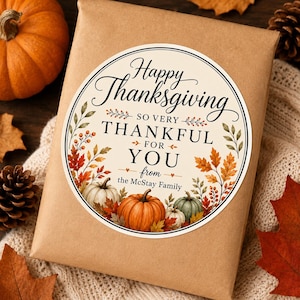 May include: A round sticker on a brown paper package featuring the text Happy Thanksgiving SO VERY THANKFUL FOR YOU from the McStay Family. The design includes illustrations of orange, white, and green pumpkins surrounded by autumn leaves.