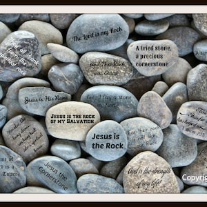 May include: A collection of gray rocks with inspirational quotes about faith and religion written on them. The quotes include "Jesus is the Rock of My Salvation", "God is the strength of my life!" and "The Lord is a Strong Tower".