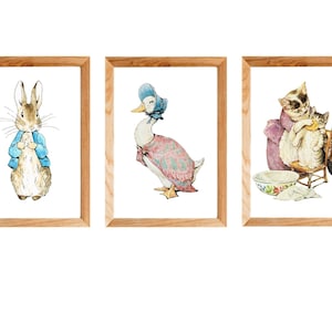 Puede incluir: Tres impresiones enmarcadas con personajes del libro infantil "El cuento de Peter Rabbit". La primera impresión muestra a Peter Rabbit con una chaqueta azul. La segunda impresión muestra a Jemima Puddle-Duck con un vestido rosa y un gorro azul. La tercera impresión muestra a la Sra. Tiggy-Winkle bañando a sus gatitos.
