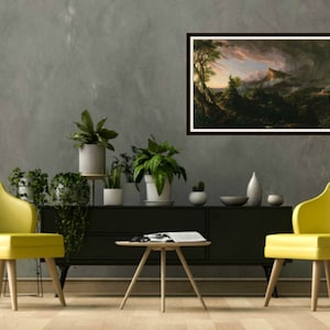 May include: A framed painting of a landscape with a mountain in the background and trees in the foreground. The sky is cloudy and there is a hint of pink in the clouds. The painting is hanging on a gray wall in a living room setting.
