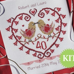 May include: Cross-stitch kit with a heart design, two kissing birds, and red floral details. The design includes the number "40", the names "Robert and Laura", and the date "Married 29th May 19". The word "KIT" is in a green starburst.