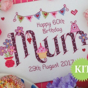 May include: Cross stitch kit featuring the word "Mum" in a pink and purple font with polka dots. The word is decorated with flowers, a cupcake, and a gift bag. The text "Happy 60th Birthday" and "29th August 2017" are also included. The kit is labelled "KIT" in a green starburst.