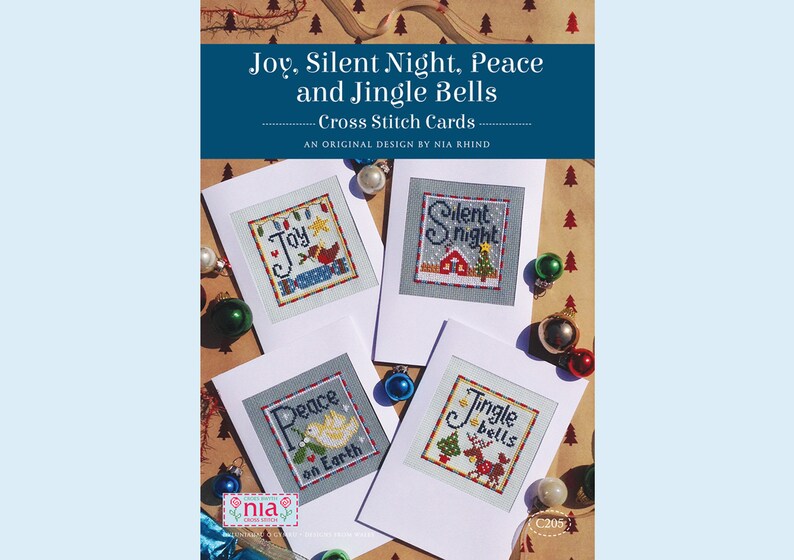 May include: Four cross stitch cards with Christmas themes. The cards feature the words "Joy", "Silent Night", "Peace on Earth", and "Jingle Bells". Each card has a different design with a festive image.