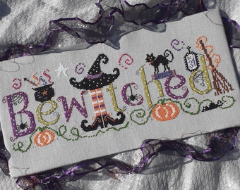 May include: Cross stitch pattern featuring the word "Bewitched" with a witch, a black cat, a cauldron, a broom, and pumpkins.