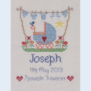 May include: A blue and white baby carriage with a red heart, surrounded by flowers, with the name Joseph, the date 11th May 2013, and the weight 7 pounds 3 ounces.