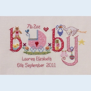 May include: A pink and white cross-stitch embroidery with the word "baby" spelled out in large letters. The letters are decorated with various baby-themed images, including a baby carriage, a teddy bear, a bird, a stork, and a rattle. The text "7lb 2oz" is above the word "baby" and the text "Lauren Elizabeth 6th September 2011" is below the word "baby".