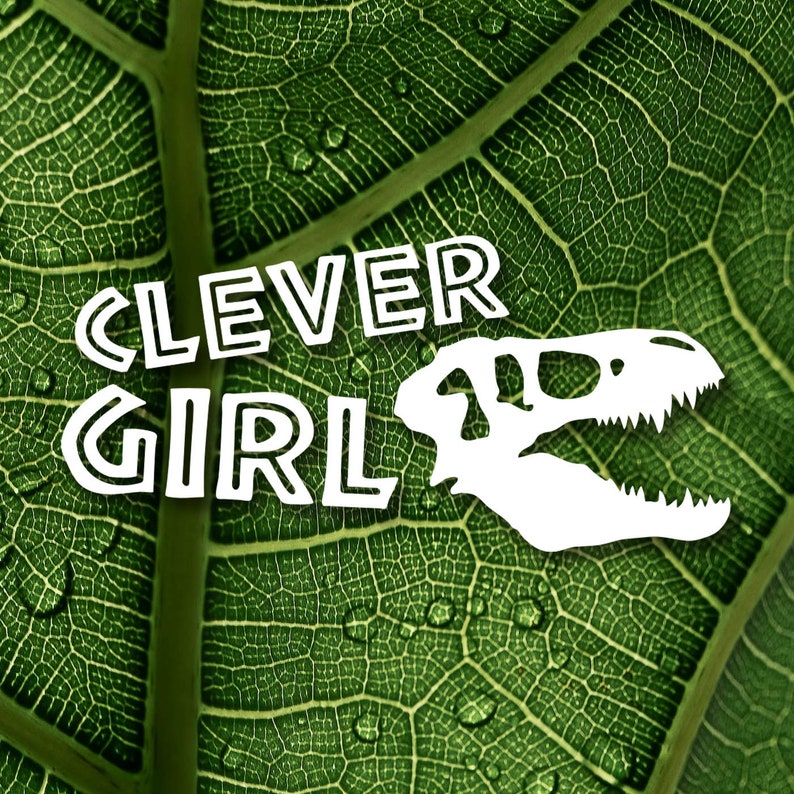 May include: White text on a green leaf background reads "Clever Girl" with a white dinosaur skull graphic to the right of the text.
