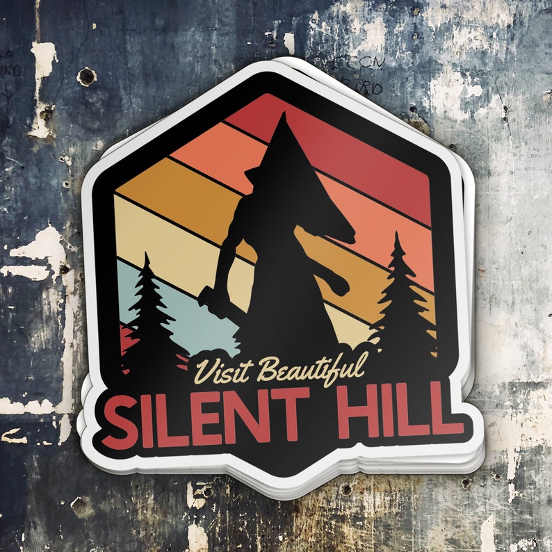 Puede incluir: Una pegatina de estilo retro con la silueta de una figura que lleva una cabeza en forma de pir&aacute;mide, de pie frente a un fondo de colores de puesta de sol con &aacute;rboles a cada lado. El texto "Visit Beautiful Silent Hill" est&aacute; impreso debajo de la figura.