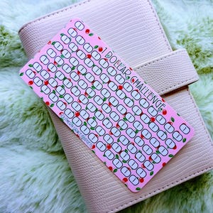 May include: A light pink, textured, rectangular savings tracker card featuring the text 1 DOLLAR CHALLENGE and SOUTHERN GRACE BUDGETS, with rows of small circles containing the number 1 and decorated with small red cherry illustrations.