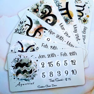 May include: A collection of white rectangular cards with zodiac signs and dates. Each card features floral designs and the name of a zodiac sign. The cards also include numbers and the text "Total Saved: $75" and "Southern Grace Decor".