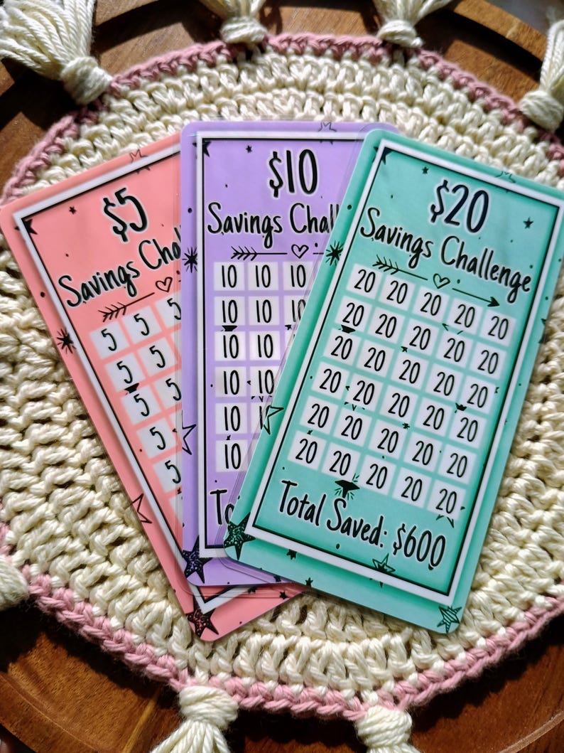 Peut inclure: Trois cartes color&eacute;es sur le th&egrave;me du d&eacute;fi d'&eacute;pargne. Les cartes sont rose, violette et turquoise. Chaque carte a un montant diff&eacute;rent&nbsp;: 5&nbsp;$, 10&nbsp;$ et 20&nbsp;$. Les cartes comportent une grille de nombres pour suivre les &eacute;conomies. La carte turquoise affiche le texte&nbsp;&laquo;&nbsp;Total &eacute;conomis&eacute;&nbsp;: 600&nbsp;$&nbsp;&raquo;.