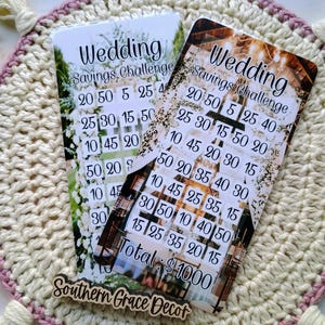 May include: Two cards with a wedding theme. The cards have a savings challenge with numbers on each card. The cards have a rustic background with a floral design. The text on the cards reads "Wedding Savings Challenge" and "Total: $1000".