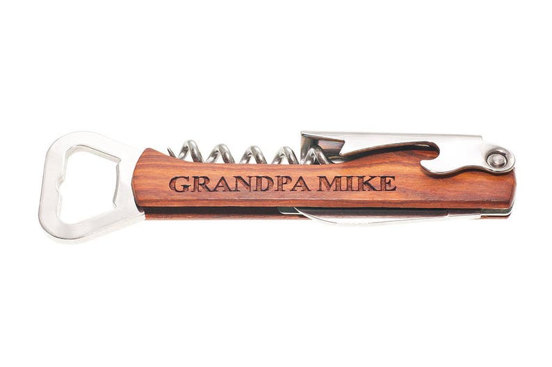 May include: A wooden bottle opener with a corkscrew and a bottle cap opener. The handle is engraved with the text "GRANDPA MIKE".