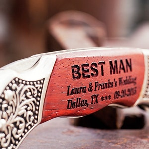 Puede incluir: Un cuchillo de bolsillo de madera roja con mango plateado grabado con las palabras "Best Man - Laura & Frank's Wedding - Dallas, TX *** 03-21-2015".
