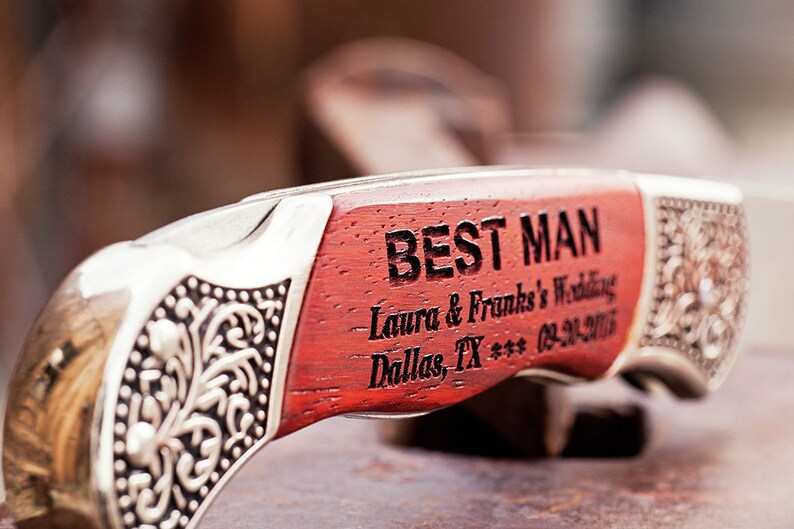 Puede incluir: Un cuchillo de bolsillo de madera roja con mango plateado grabado con las palabras "Best Man - Laura & Frank's Wedding - Dallas, TX *** 03-21-2015".