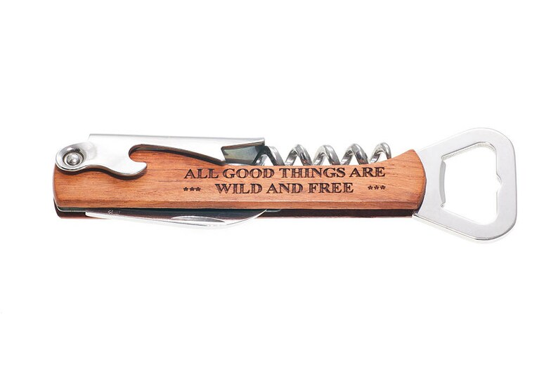 May include: A wooden handled multi-tool with a bottle opener, corkscrew, and a small knife. The handle is engraved with the text "All good things are *** wild and free ***".