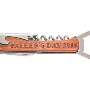 May include: A wooden handled bottle opener with a corkscrew and a bottle opener. The handle is engraved with the text "Father's Day 2015".