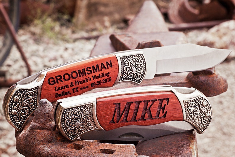 Puede incluir: Dos navajas de bolsillo con mangos de madera. La navaja superior est&aacute; grabada con "GROOMSMAN Laura & Frank's Wedding Dallas, TX *** 09-20-2015". La navaja inferior est&aacute; grabada con "MIKE".