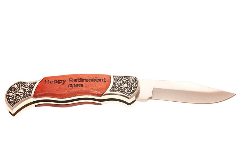 Puede incluir: Un cuchillo de bolsillo plateado con mango de madera grabado con "Happy Retirement 12/16/15".