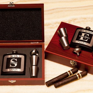 May include: Two wooden gift boxes with engraved metal hip flasks, shot glasses, and cigars. The flasks are personalized with names and initials. One box has the text "Best Man" and the other has the text "Groom".