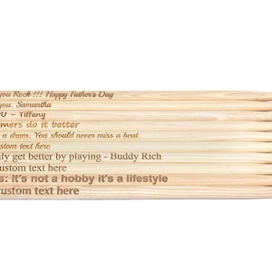 May include: A set of wooden drumsticks with personalized engravings. The text reads "Dad, you Rock!!! Happy Father's Day", "I love you. Samantha", "I YOU - Tiffany", "Drummers do it better", "Love is a drum. You should never miss a beat.", "Your custom text here", "You only get better by playing - Buddy Rich", "Your custom text here", "Drums: It's not a hobby it's a lifestyle", "Your custom text here".
