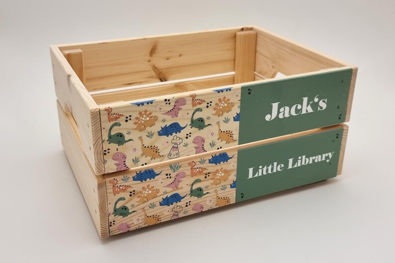 Wooden book storage crate with a dinosaur theme, featuring a personalized name panel. Ideal for kids’ rooms, nursery decor, and book organization.