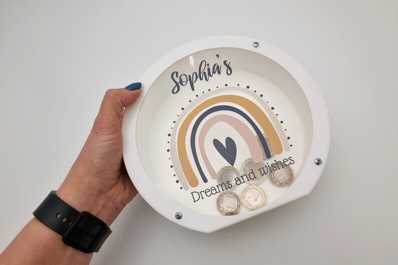 May include: White wooden piggy bank with a rainbow design and the text "Sophia's Dreams and wishes".