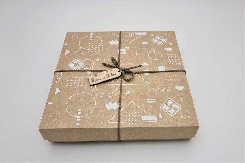 May include: A brown cardboard gift box with a geometric pattern in white. The box is tied with brown twine and has a wooden tag that says "Made with love".