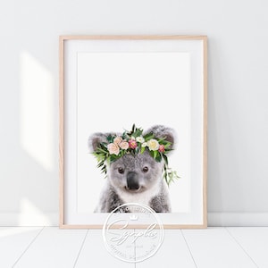 Könnte beinhalten: Ein süßes Koala, das eine Blumenkrone mit rosa, weißen und gelben Blumen trägt. Das Koala schaut mit einem süßen Ausdruck in die Kamera.