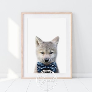 Peut inclure: Un chiot loup gris portant un nœud papillon bleu et blanc à carreaux. Le chiot regarde directement la caméra. L'image est sur un fond blanc avec le texte "The Original" et un logo pour "Sygplus Baby Animals" en bas.