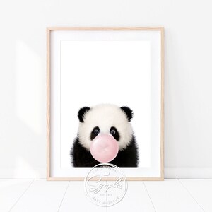 Könnte beinhalten: Ein schwarz-weißes Pandabärchen mit rosa Kaugummi im Maul. Der Panda schaut direkt auf den Betrachter. Das Bild ist vor einem weißen Hintergrund.
