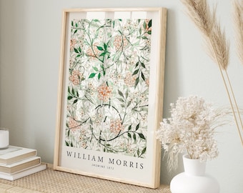Könnte beinhalten: Ein gerahmter Druck eines Blumendesigns von William Morris mit dem Titel "Jasmine 1872". Der Druck ist in einem hellen Holzrahmen und hängt an einer weißen Wand. Der Druck zeigt ein grünes und weißes Blumenmuster mit orangefarbenen Akzenten.