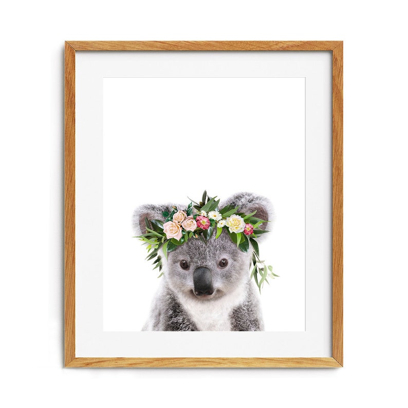 May include: A cute koala wearing a flower crown with pink, white, and yellow flowers. The koala is looking directly at the camera.