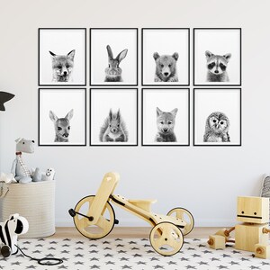May include: A set of eight black and white animal prints in frames, featuring a fox, rabbit, bear, raccoon, deer, squirrel, wolf, and owl. The prints are arranged in a grid pattern on a white wall.