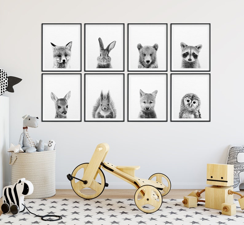 May include: A set of eight black and white animal prints in frames, featuring a fox, rabbit, bear, raccoon, deer, squirrel, wolf, and owl. The prints are arranged in a grid pattern on a white wall.