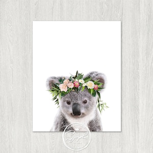 May include: A cute koala wearing a flower crown with pink, white, and yellow flowers. The koala is looking at the camera with a sweet expression.