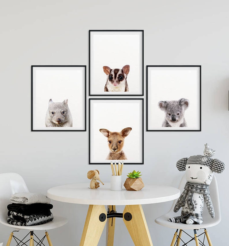 May include: Four black framed prints of Australian animals. The prints feature a koala, a sugar glider, a wombat, and a joey kangaroo. The prints are arranged in a grid pattern on a white wall.