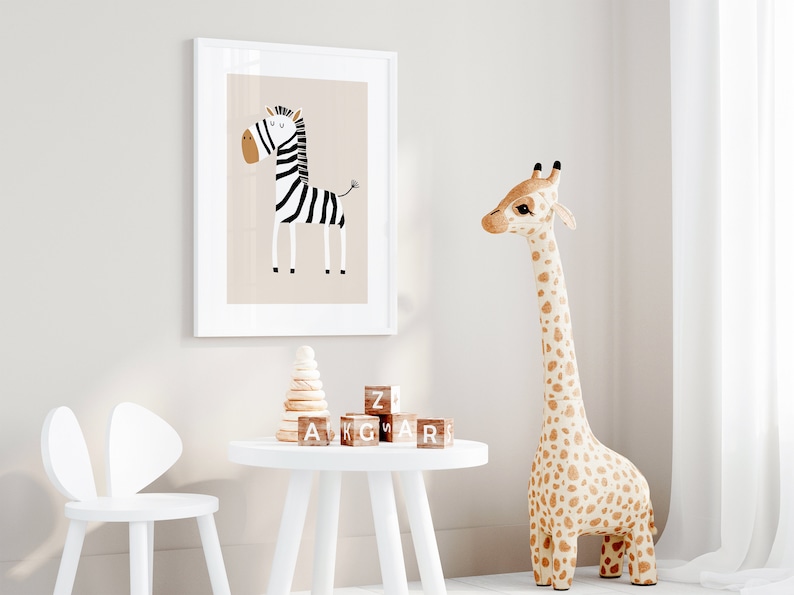 May include: A white framed print of a black and white zebra with a brown background. A white table with a wooden stacking toy and wooden alphabet blocks. A large stuffed giraffe with brown spots stands next to the table. A white chair with bunny ears is in the foreground.