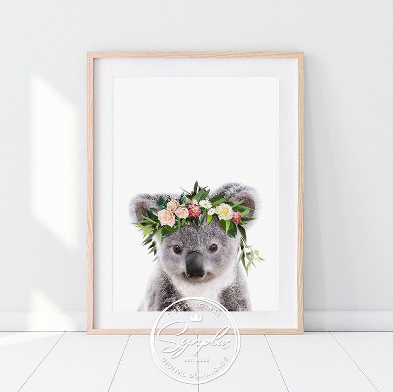May include: A cute koala wearing a flower crown with pink, white, and yellow flowers. The koala is looking at the camera with a sweet expression.