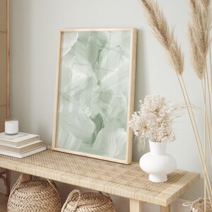 May include: A wooden bench with a woven rattan top, two woven baskets, and a vase with dried flowers. A framed abstract painting with green brushstrokes hangs above the bench.