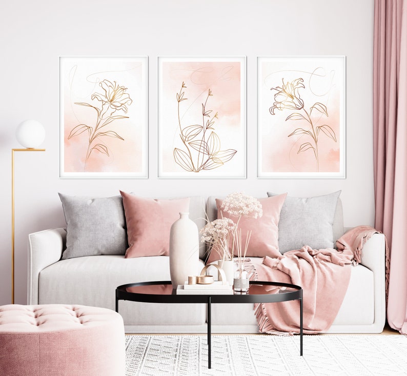 May include: Three framed prints with a minimalist design featuring gold line drawings of flowers and leaves on a pink watercolor background.